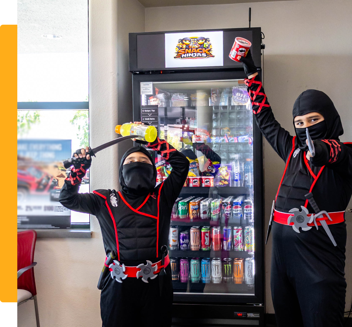 Two children in ninja costumes by snack fridge